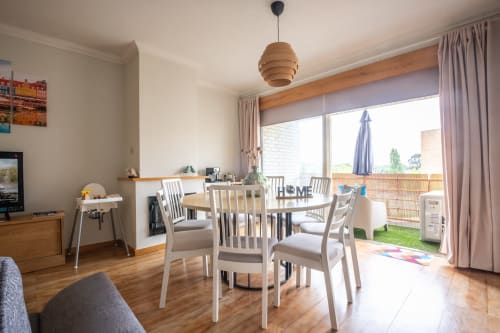 Heller Essbereich mit Holztisch, weißen Stühlen und Glasschiebetüren, die sich zum privaten Garten von EcoHost öffnen