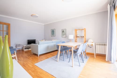 Modernes Wohn-Esszimmer mit Holztisch, blauen Stühlen, hellem Sofa und Küche im EcoHost Matosinhos
