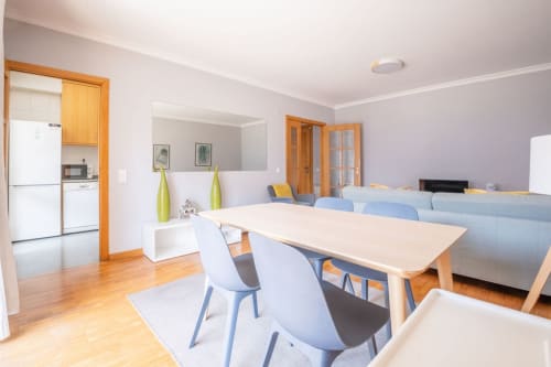 Moderner offener Wohnbereich im EcoHost-Apartment in Matosinhos mit Esstisch, blauen Stühlen, Sofa und ausgestatteter Küche