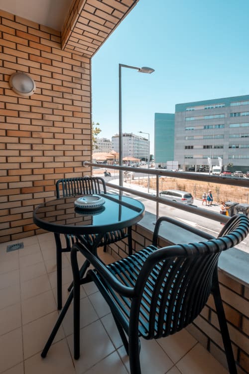 Balkonbereich im EcoHost Matosinhos mit Stadtblick, blauer Tisch und schwarze Stühle mit Ausblick auf die Stadtlandschaft