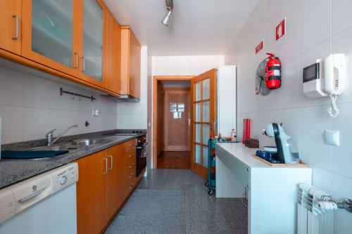 Moderne Küche in der OceanSide-Wohnung in Matosinhos mit orangefarbenen Schränken, Granitarbeitsplatten und vollständig ausgestatteten Geräten