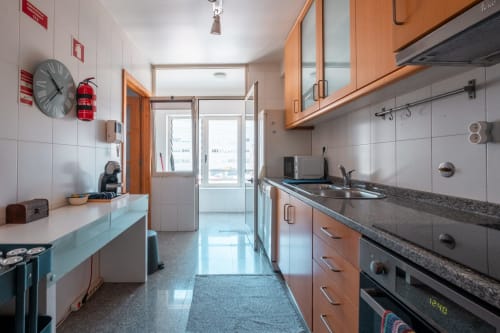 Moderne Küchenzeile im EcoHost OceanSide Apartment in Matosinhos mit Holzschränken, Edelstahlgeräten und Stadtblick