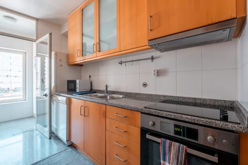 Moderne orange Küche mit Edelstahlgeräten, Granitarbeitsplatte und Stadtblick im EcoHost Matosinhos