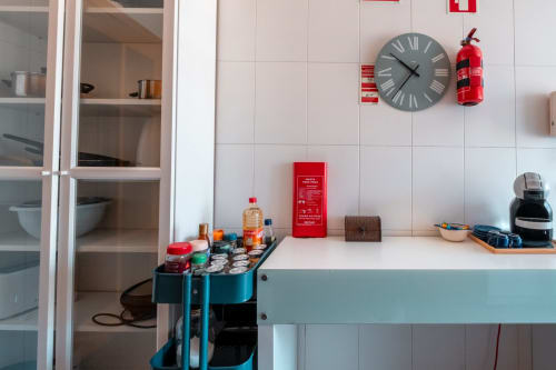 Moderne Küche in EcoHost-Apartment mit weißen Fliesen, Nespresso-Maschine, Feuerlöscher, Wanduhr und ausgestatteten Arbeitsplatten