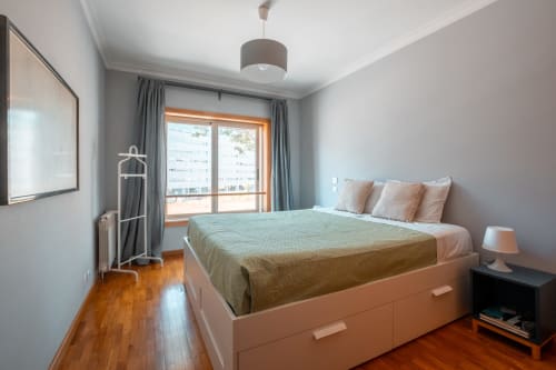 OceanSide Apartment-Schlafzimmer in Matosinhos mit Stadtblick, orangefarbenem Bettrahmen, Holzfußboden und Balkonzugang