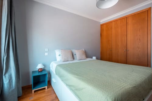 Helles Schlafzimmer im EcoHost Matosinhos mit Queensize-Bett, grüner Bettwäsche, hölzernem Kleiderschrank, blauem Nachttisch und Stadtblick
