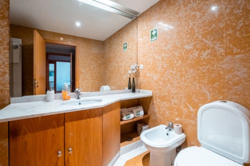 Modernes Badezimmer im EcoHost Oceanside Apartment in Matosinhos mit Holzwaschtisch, Bidet, Toilette und Korkstruktur-Wänden