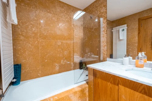Modernes Badezimmer im OceanSide EcoHost Apartment in Matosinhos mit Terrakotta-Marmorfliesen, weißem Waschtisch und begehbarer Glastür Dusche