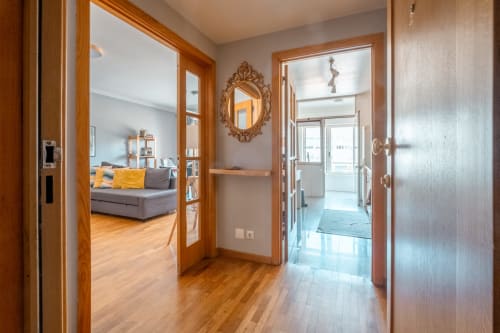 Moderner Flur der OceanSide-Wohnung in Matosinhos mit Holztüren, verziertem Spiegel und Stadtblick