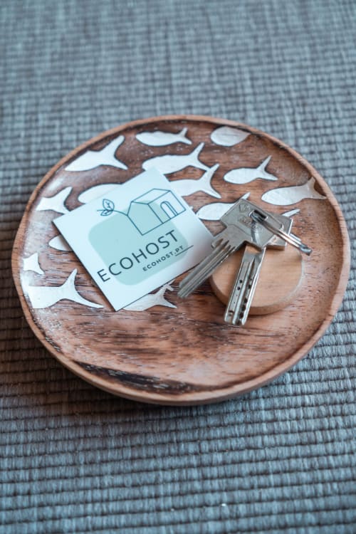 EcoHost-Schlüsselkarte und Schlüssel auf einer Holzschale mit Fischmustern, Willkommensgabe im Apartment Matosinhos