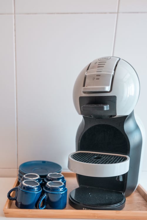 Nespresso-Kaffeemaschine mit blauen Tassen auf Holztablett in der Küche des EcoHost OceanSide Apartments