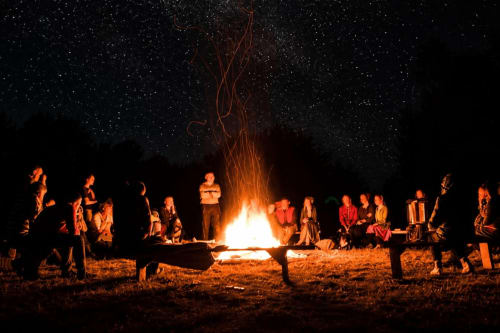 Groupe réuni autour d'un feu de camp sous un ciel étoilé au Gîte La Truite d'Or à Lods, France