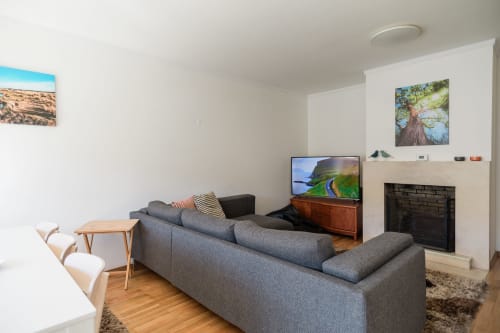 Modernes Wohnzimmer mit grauem Sofa, Fernseher, Kamin und Naturkunst im EcoHost Apartment in Arcozelo, Portugal