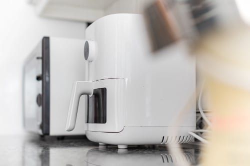 Weiße Kaffeemaschine mit schwarzem Griff auf der Küchentheke des EcoHost-Apartments