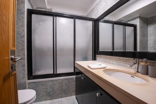 Modernes Badezimmer im EcoHost Gaia Beach&Golf mit Doppelwaschtisch, Duschkabine aus Mattglas und grauen Wandfliesen