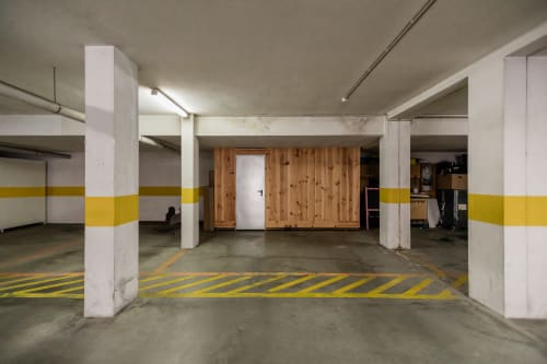 Unterirdische Parkgarage des EcoHost Gaia Beach&Golf in Arcozelo mit gelb-weißen Markierungen und Holzlagerraum
