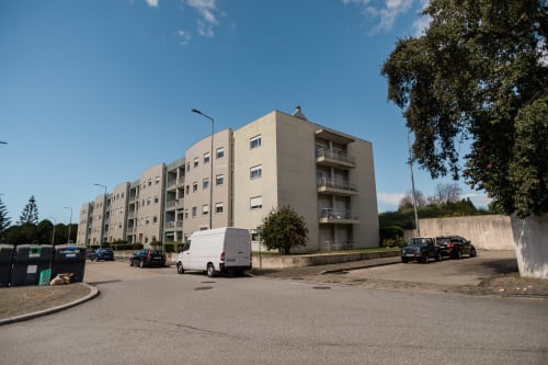 EcoHost-Apartmentkomplex in Arcozelo mit beigen Gebäuden, Parkplatz und umliegender Grünfläche unter klarem Himmel