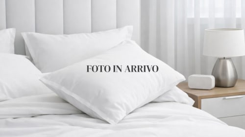Camera da letto lussuosa di THE V Collection Milano con cuscini bianchi, lenzuola fresche e moderna lampada da comodino