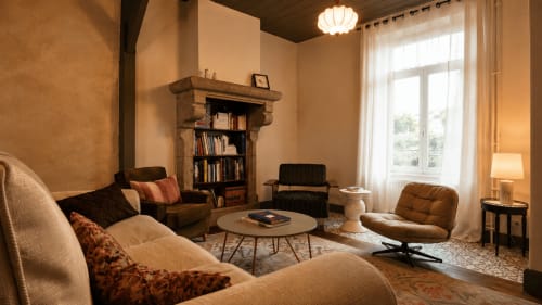 Salon chaleureux à La Maison 1903 B&B à Trévou-Tréguignec avec sièges confortables, cheminée et lumière naturelle