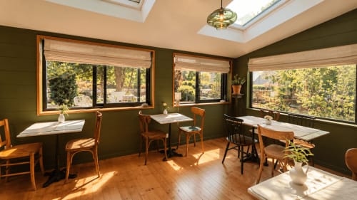 Salle à manger lumineuse de la Maison 1903 avec vue forêt, mobilier bois et puits de lumière