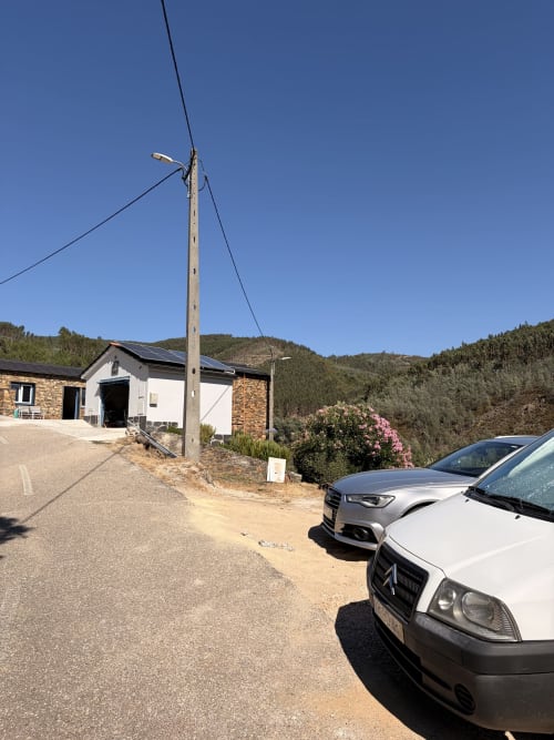 Casa de montanha Casa Relva da Mó com carros estacionados, poste de serviços e colinas arborizadas sob céu limpo