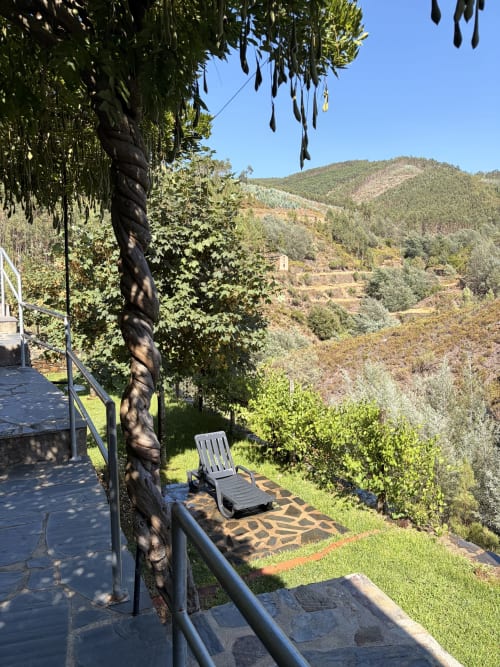 Terraço sombreado com espreguiçadeira com vista para montanhas florestadas na Casas do Sinhel em Portugal