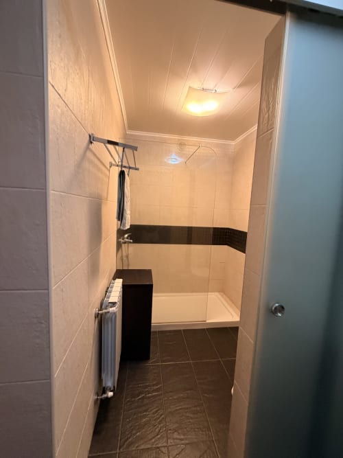 Banheiro moderno com duche aberto, piso em azulejo escuro e iluminação de teto na quinta Casa Relva da Mó em Portugal