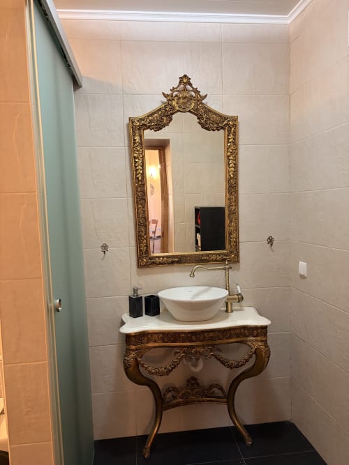 Espelho ornamentado com moldura dourada acima da pia branca da Casa Relva da Mó em Casas do Sinhel, Portugal