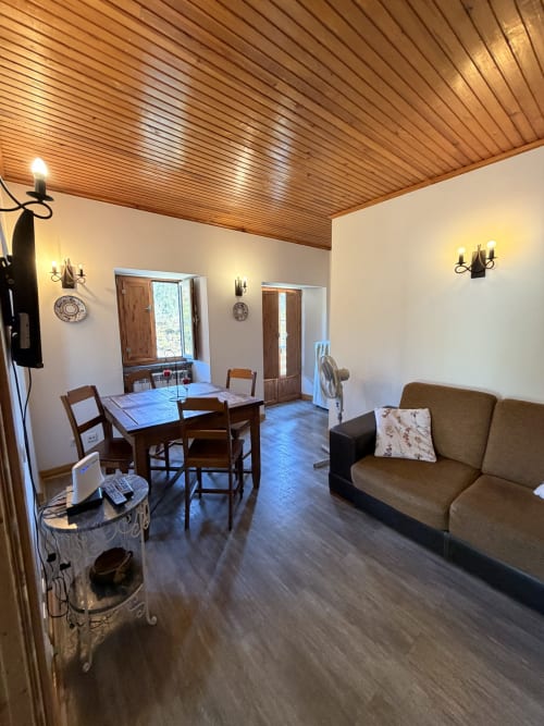 Luminosa sala de estar em Casas do Sinhel com teto de madeira, mesa de jantar, sofá e vistas para as montanhas pelas janelas