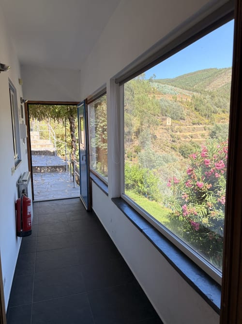 Corredor luminoso com grandes janelas com vista para as montanhas na quinta Casa Relva da Mó, Portugal