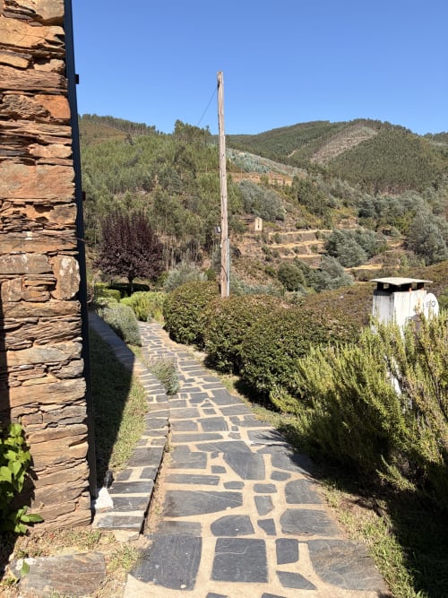 Caminho de pedra levando à casa de hóspedes com vistas de montanha e sebes verdes em Casas do Sinhel, Portugal