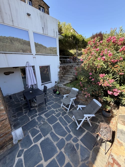 Pátio da Casa da Adega com vista para a montanha, flores rosas, espreguiçadeiras e chuveiro externo em Casas do Sinhel