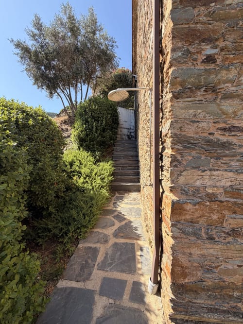 Caminho de pedra rústica levando à Casa da Adega com vista de oliveira e montanhas