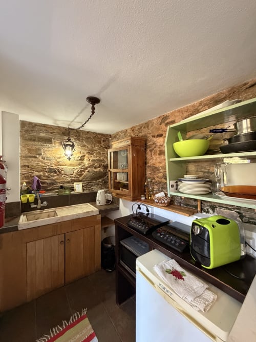 Cozinha da Casa da Adega com paredes de pedra, móveis em madeira e detalhes verde limão no Casas do Sinhel, Relva da Mó