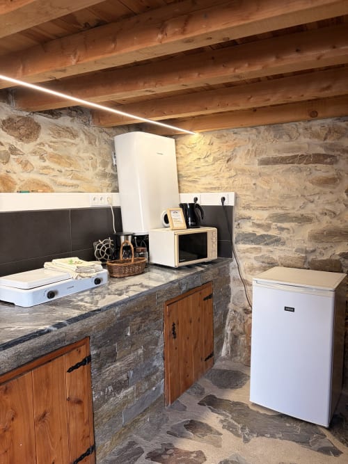 Cozinha moderna em pedra na villa Casa da Capela em Casas do Sinhel, com eletrodomésticos brancos e marcenaria de madeira