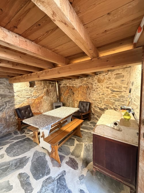 Interior rústico de villa de pedra em Casas do Sinhel com vigas de madeira, mesa de jantar e vistas para a montanha
