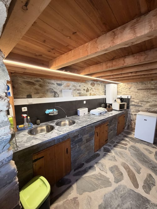 Cozinha moderna na vila Casa da Capela em Casas do Sinhel com paredes de pedra, vigas de madeira, duas pias e aço inoxidável