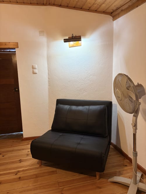 Cadeira futon em couro preto na sala de estar da villa Casa da Capela com ventilador e teto de madeira em Casas do Sinhel, Portugal
