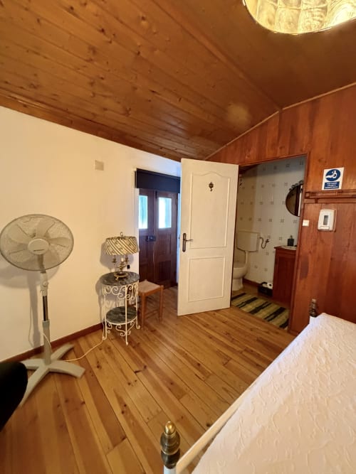 Quarto espaçoso na villa Casa da Capela em Casas do Sinhel com teto de madeira, ventilador, banheiro privativo com chuveiro e