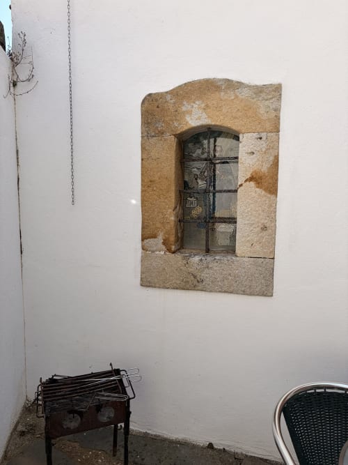 Janela com moldura de pedra histórica e porta de metal na quinta Casas do Sinhel em Roda Fundeira, Portugal