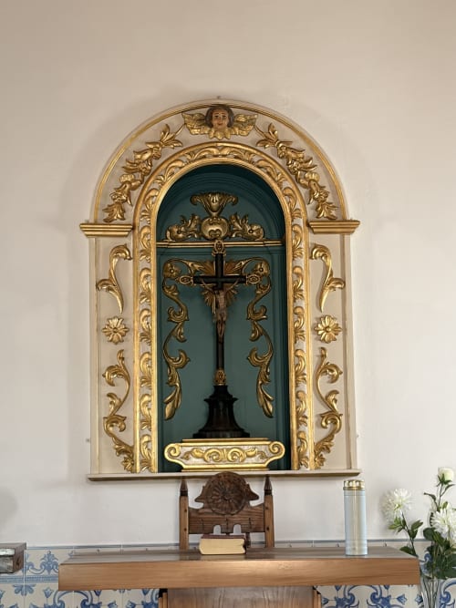 Altar ornado da capela com crucifixo e moldura decorativa dourada na villa Casas do Sinhel