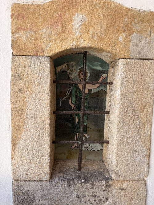 Antiga porta de pedra com entrada em arco e grades de metal rústico na vila Casas do Sinhel em Roda Fundeira, Portugal