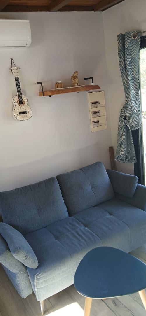 Salon moderne du Chalet Eléonore au Domaine de Jade : canapé bleu, guitare murale et vue sur les montagnes