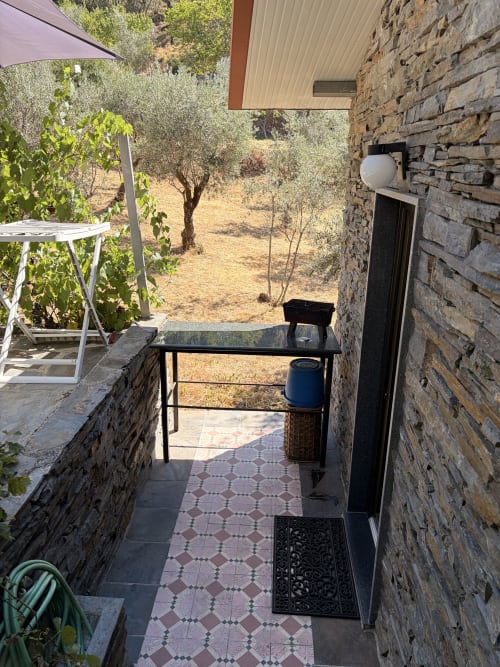 Pátio coberto na quinta Casa das Oliveiras em Alvares com vista para olivais, paredes de pedra e zona de refeições exterior