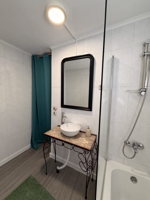 Banheiro moderno com azulejos brancos, espelho com moldura preta, pia redonda, área de duche e cortina azul-petróleo na villa Casa das Oliveiras