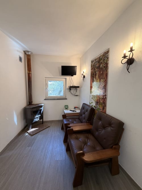 Sala de estar aconchegante da vila Casa das Oliveiras em Álvares com móveis de couro, lareira, TV e tapeçaria decorativa