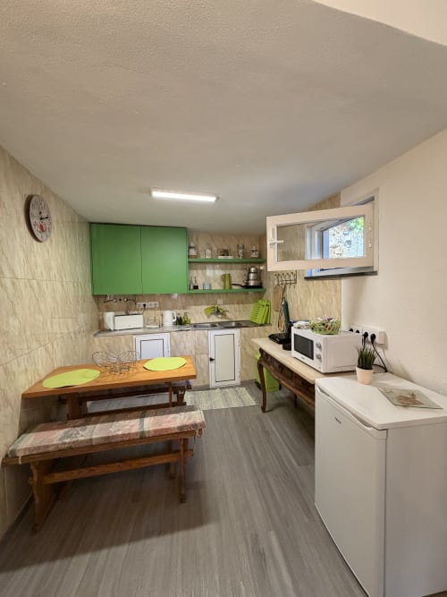 Cozinha moderna na villa Casa das Oliveiras em Casas do Sinhel, Portugal com armários verdes, mesa de jantar em madeira e