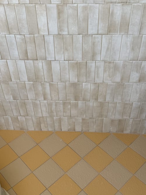 Détail du carrelage de la salle de bains à La Grange Aux Etangs, montrant un sol en chevrons dans les tons moutarde et beige avec finitions verticales