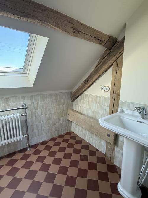 Salle de bains La Rose sauvage à La Grange Aux Etangs avec carrelage à damier, lavabo sur colonne et poutres apparentes