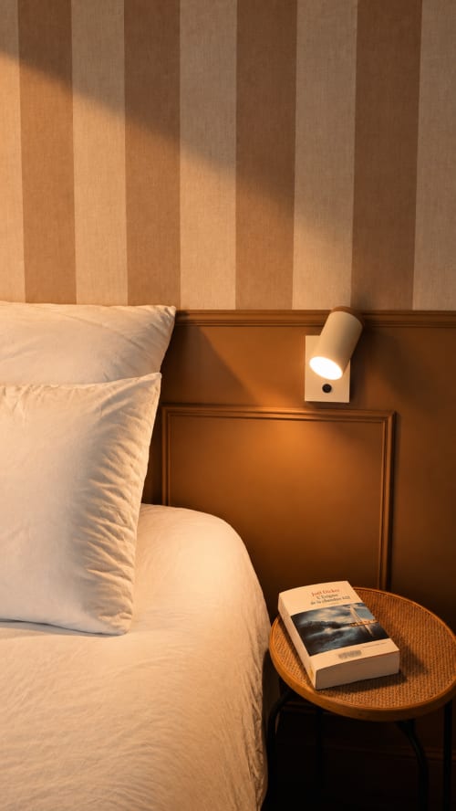 Chambre douillette à La Maison 1903 B&B à Trévou-Tréguignec avec mur rayé, literie blanche, lampe de lecture et livre sur table ronde